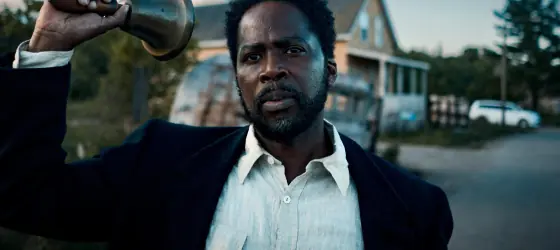 Harold Perrineau walking in a street with a bell in hand in 
